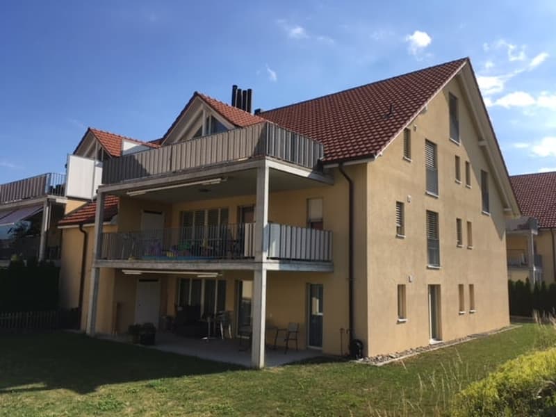 3-story apartment building with beige exterior, red tile roof, and balconies on each floor.
