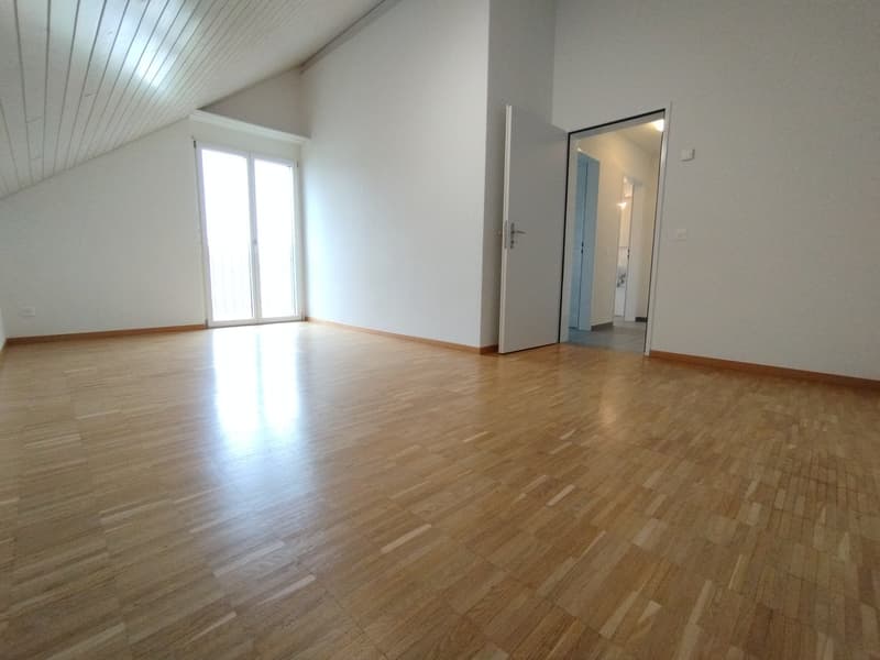 empty room with wooden floors, white walls, and windows