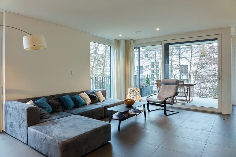 L-shaped sofa, coffee table, armchairs, balcony with outdoor table and chairs, floor lamp, glass doors