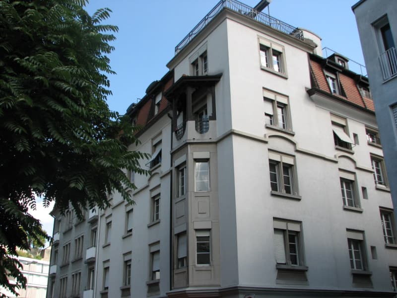 Apartment building, white exterior, red roof, several windows, balconies