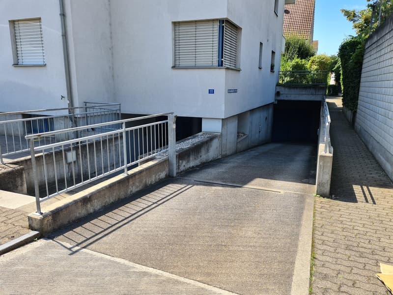 White building with garage access through a sloped driveway