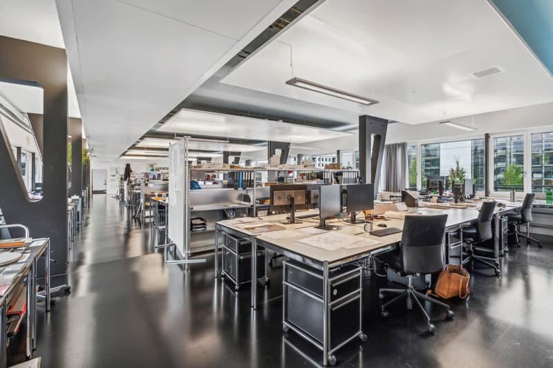 modern office space, several desks with computers, chairs, bookshelves, white walls, black floors, ceiling lamps
