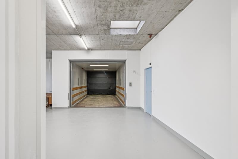 large open garage, gray concrete walls, white floors, large door