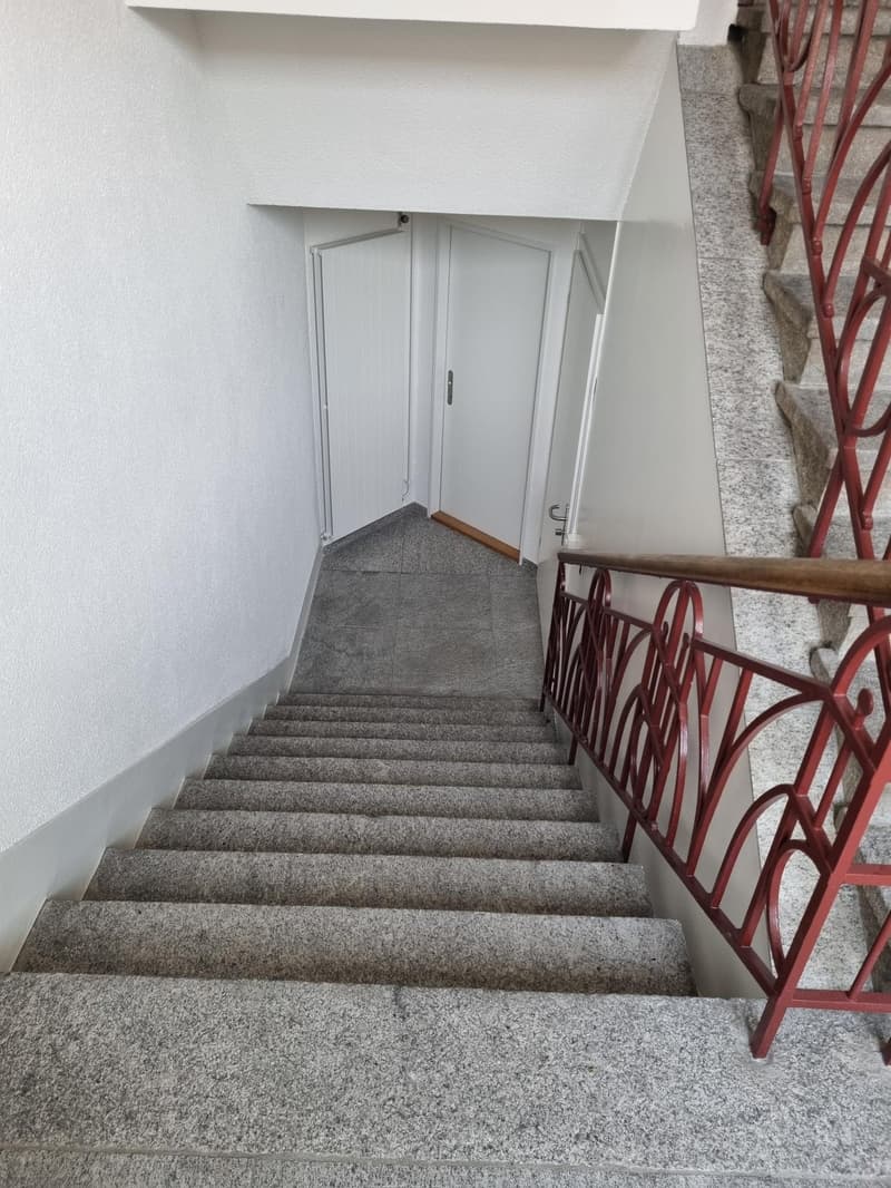 Gray marble steps, white walls, red railings, two white doors