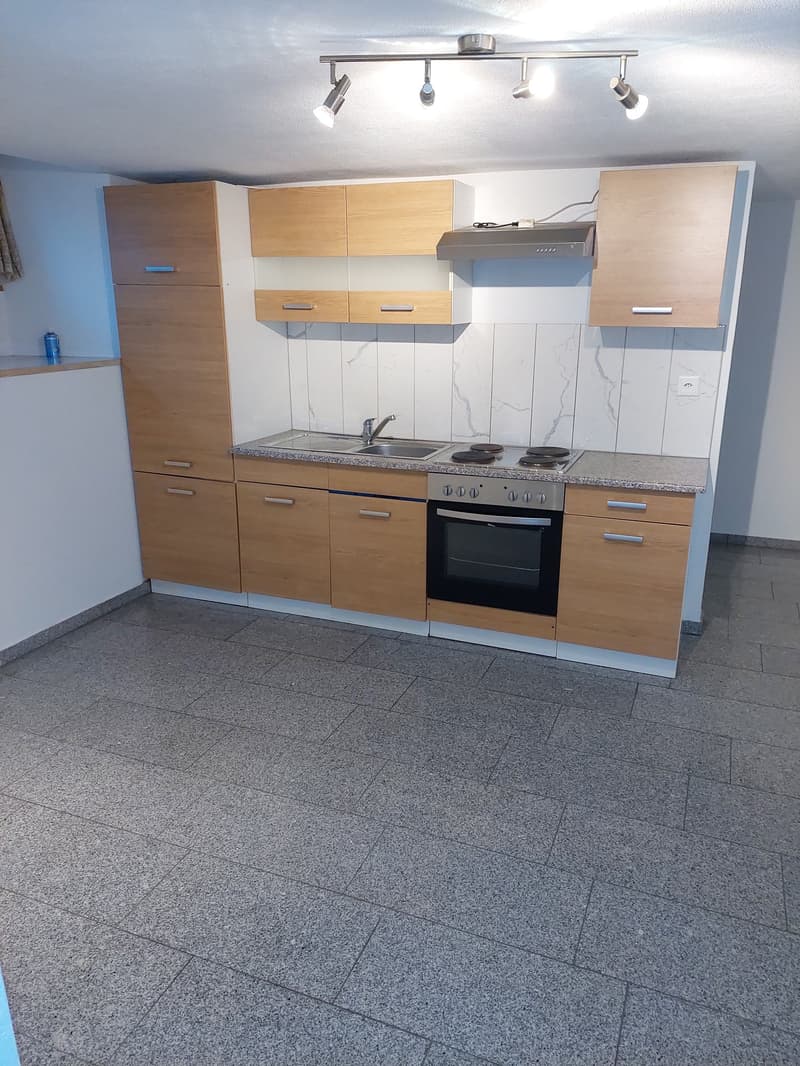Modern kitchen with light wood cabinets, granite countertop, built-in oven and dishwasher, tiled floor