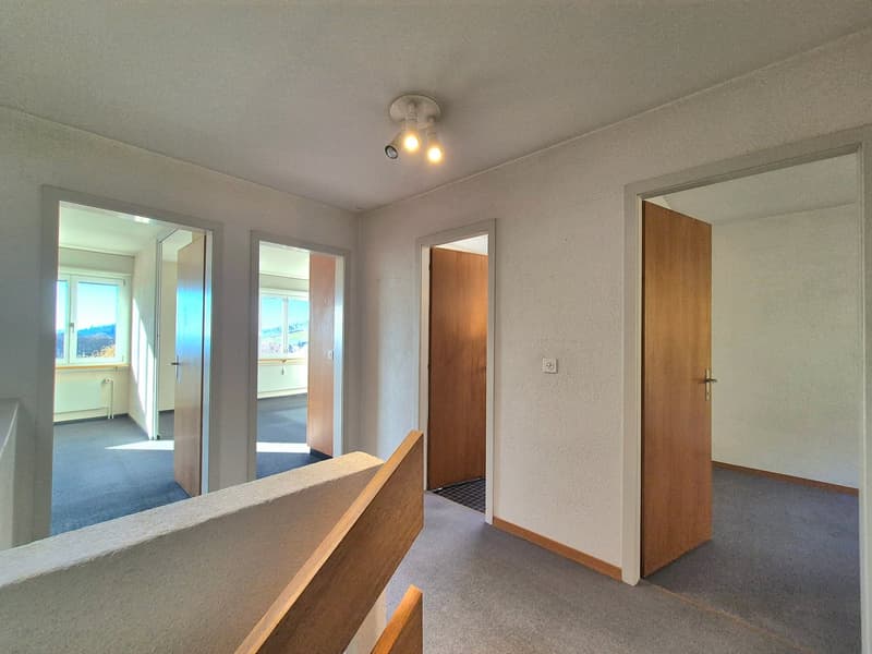 staircase leading to multiple doors, carpeted floor, windows, ceiling lights