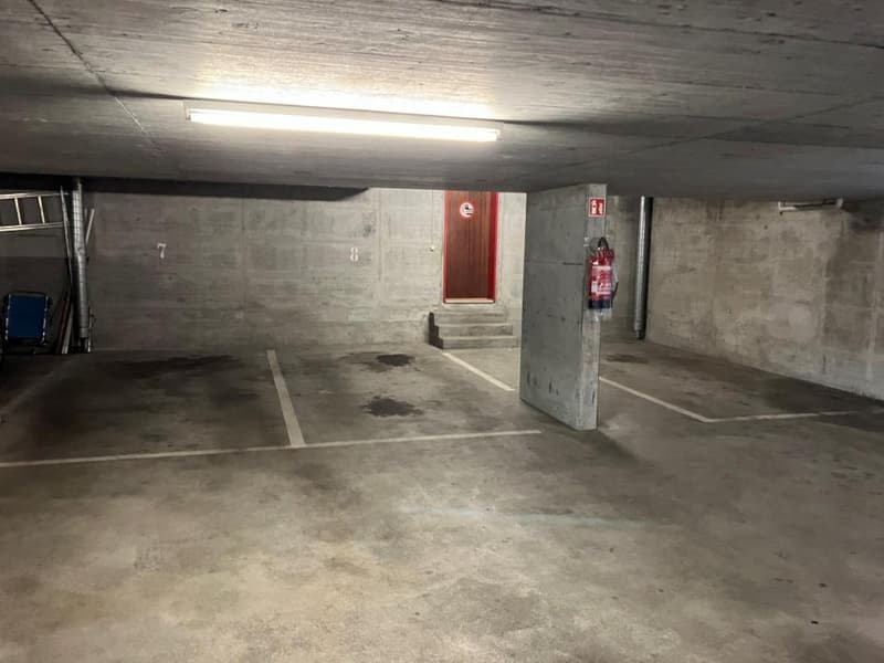 Concrete walls and floor, fluorescent lighting, numbered parking spots, fire extinguisher