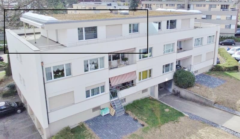 3 story apartment building, white exterior, multiple balconies, green roof, parking area, plants