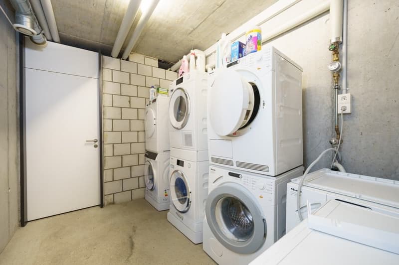 stacked washing machines and dryers, white door, brick wall, power outlet