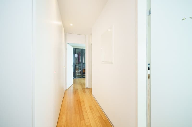 white walls, wooden floor, open door leading to another room