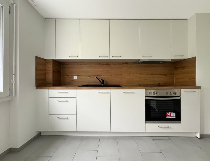 white cupboards, wooden countertop, stainless steel oven and stove, black sink, white tiled floor