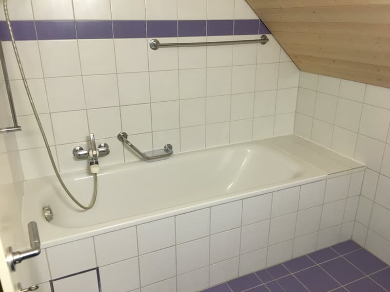 Bathroom with white tiles, bathtub, shower head, and wooden ceiling
