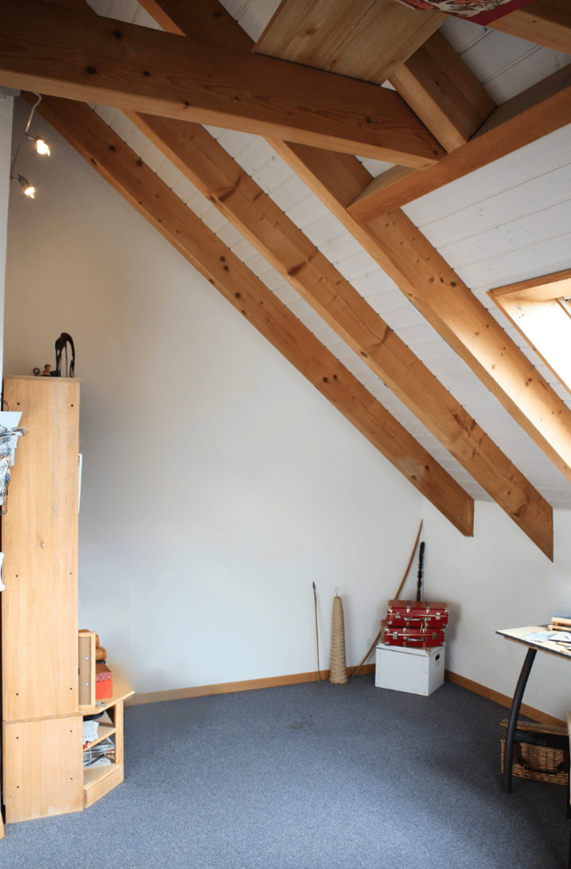 wooden ceiling, white walls, blue carpet, wooden cabinet, white box, red suitcases, table