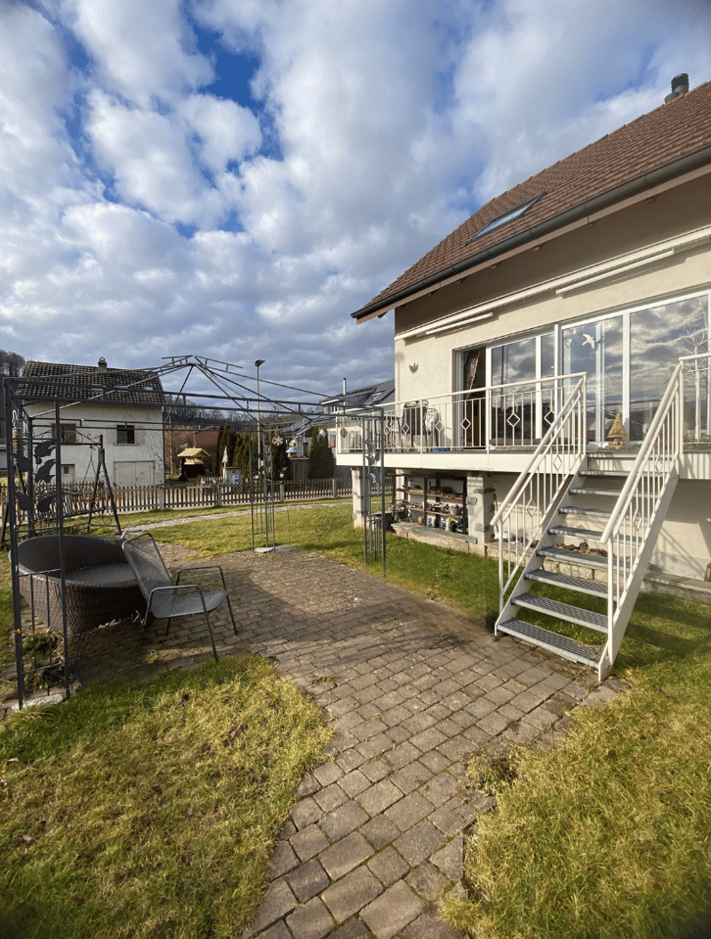 large paved garden, white handrails, stairs to the house, metal gazebo, chairs