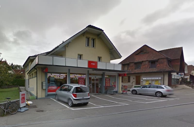 2-story commercial building with a grocery store on the ground floor, parking lot in front, and residential units on the upper floor