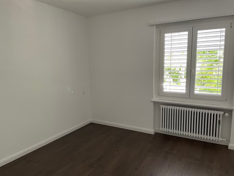 empty room, white walls, wooden floor, white radiator, window with shutters