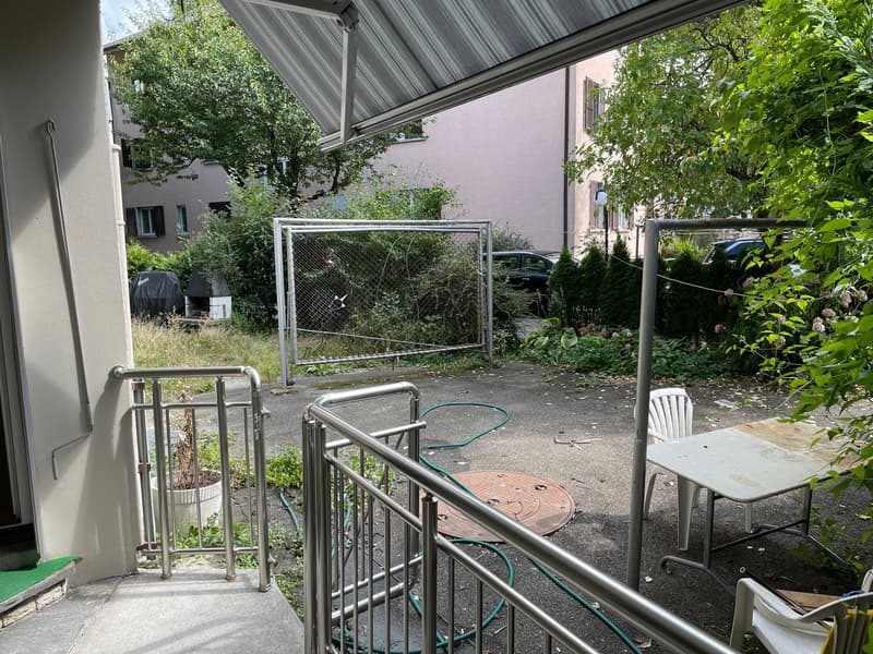 Outdoor area with metal railings, a table, chairs, a metal gate, and a covered area with a metal awning.