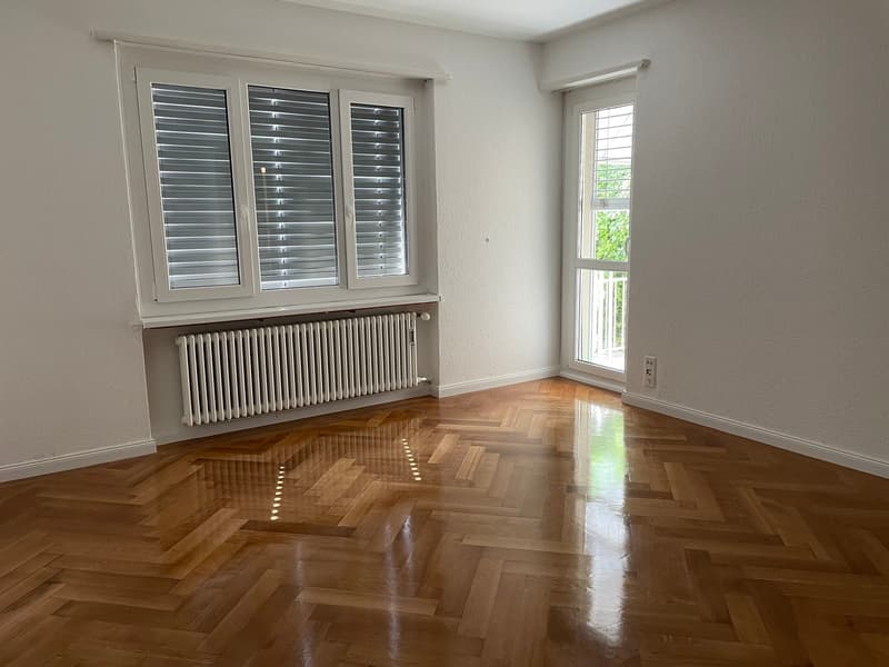 empty room, wooden parquet floor, white walls, two windows, white radiator