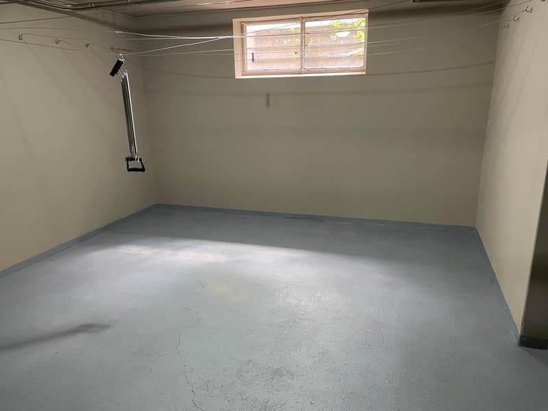 Empty room with white walls, concrete floor, small window, pull-up bar