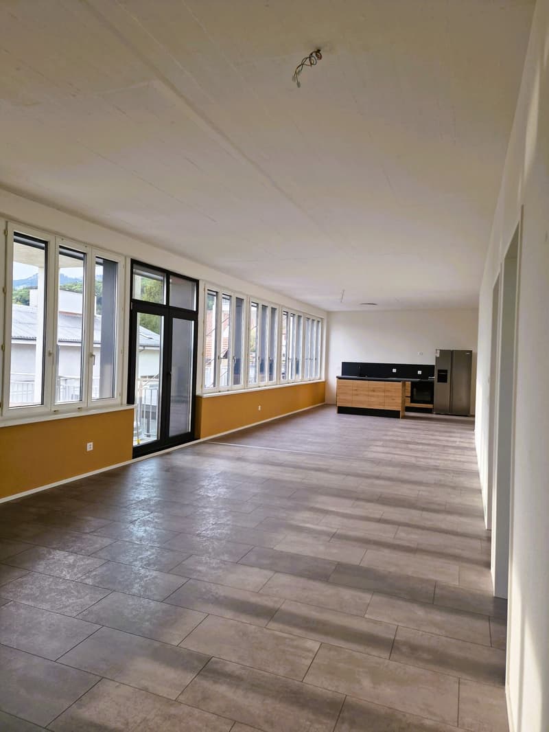 large room, large windows, wooden floor, kitchen area, refrigerator