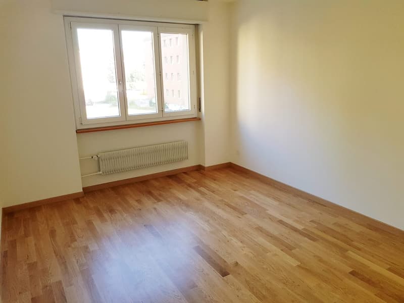 hardwood floor, large window, white radiator, blank walls
