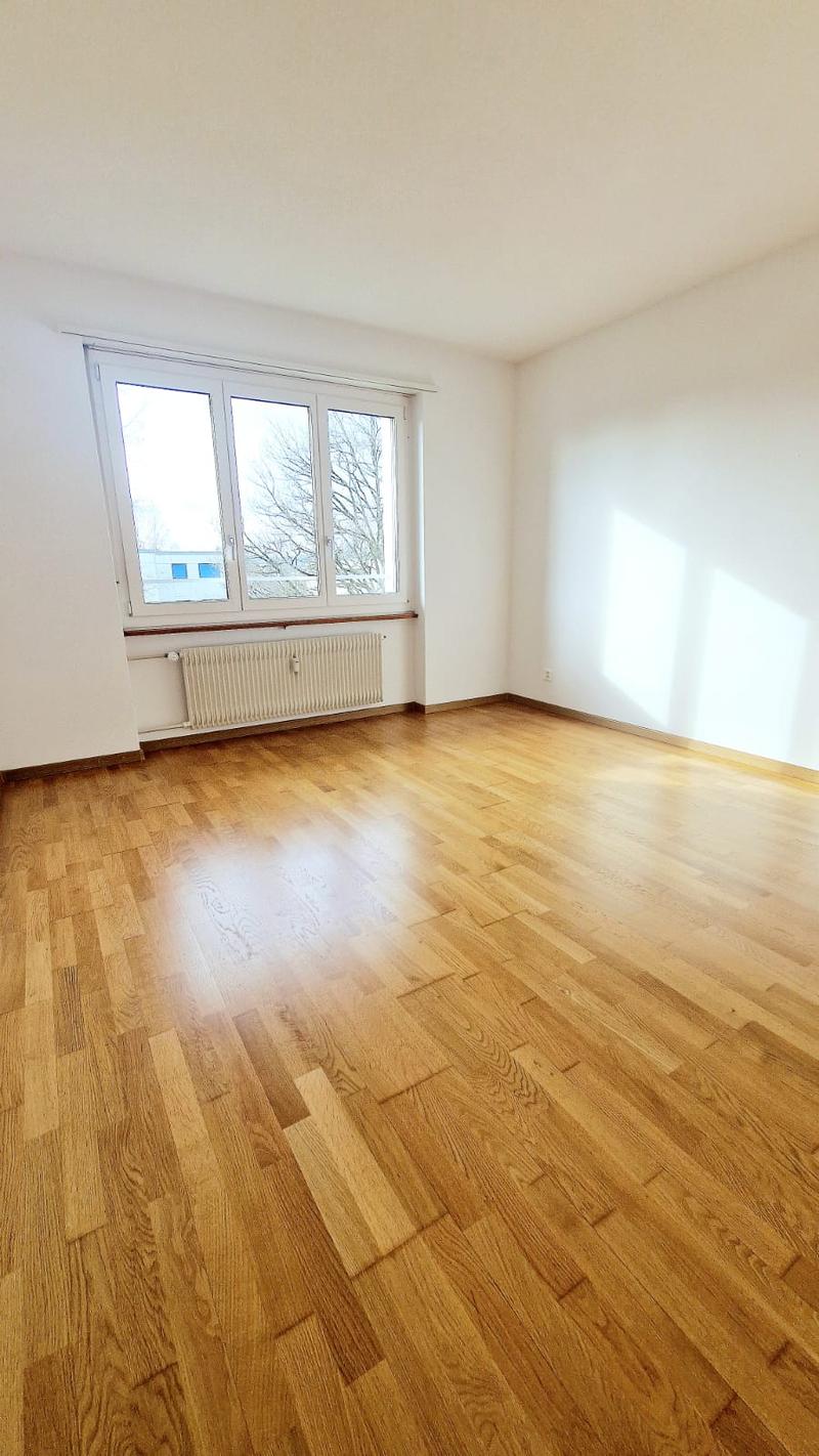 Empty room, wooden floor, windows with white frames, radiator, natural light