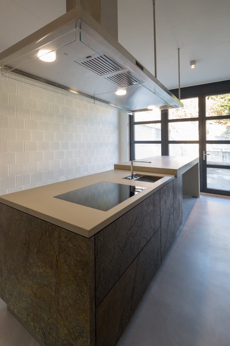 modern kitchen with island, large sink, induction cooktop, wooden cabinets, white tiled wall, large windows