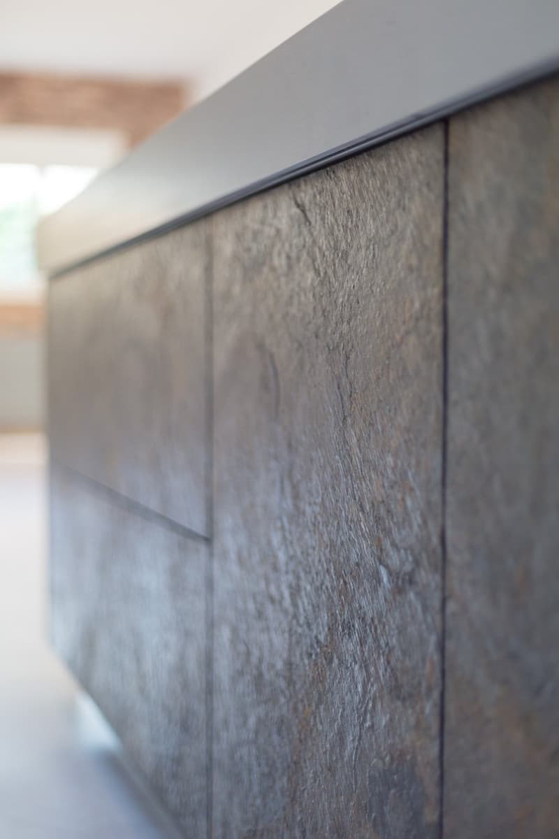 Close-up of a wooden cabinet with a gray countertop, wooden texture, and a slightly curved edge.