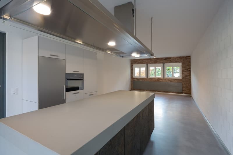 modern kitchen with white cabinets, stainless steel appliances, large island, brick wall, large windows