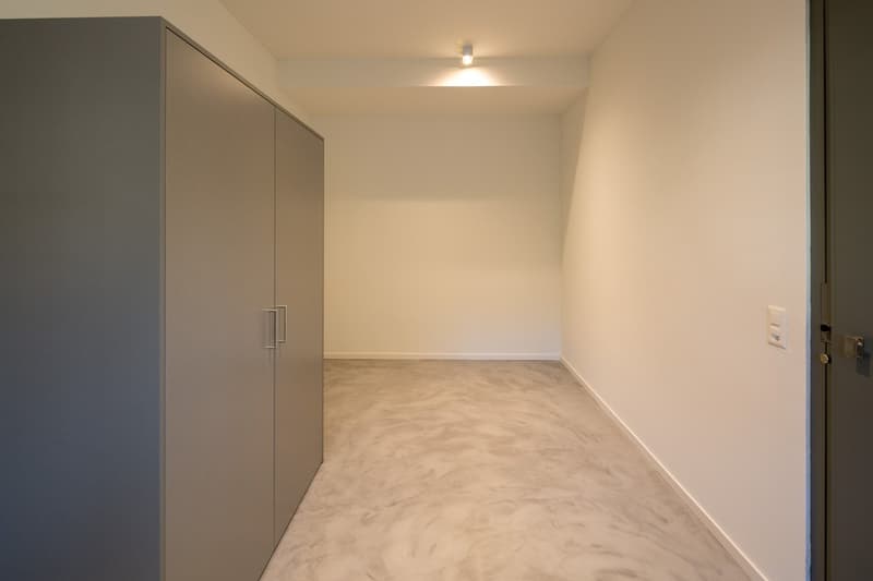 Empty room with white walls, gray cabinets, and a gray floor.