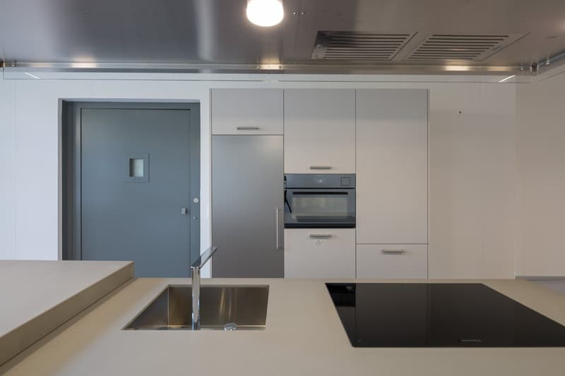 modern kitchen with stainless steel sink, induction hob, built-in oven, white cabinets, gray door, gray floor