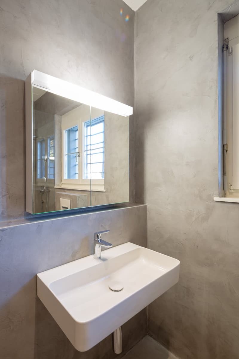 Bathroom with white sink, mirror, and gray walls