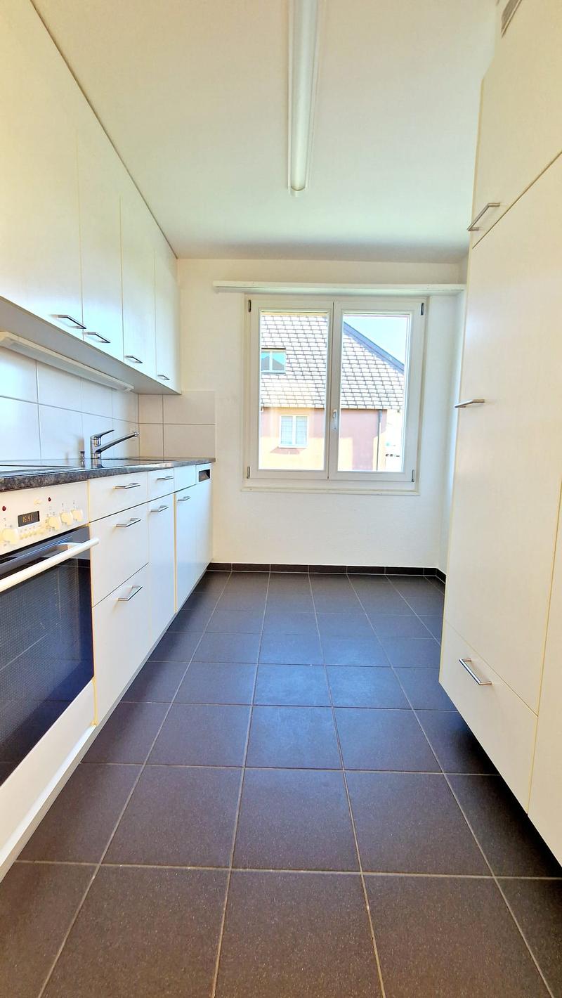 modern kitchen with white cabinets, tiled floor, window with view of the outside