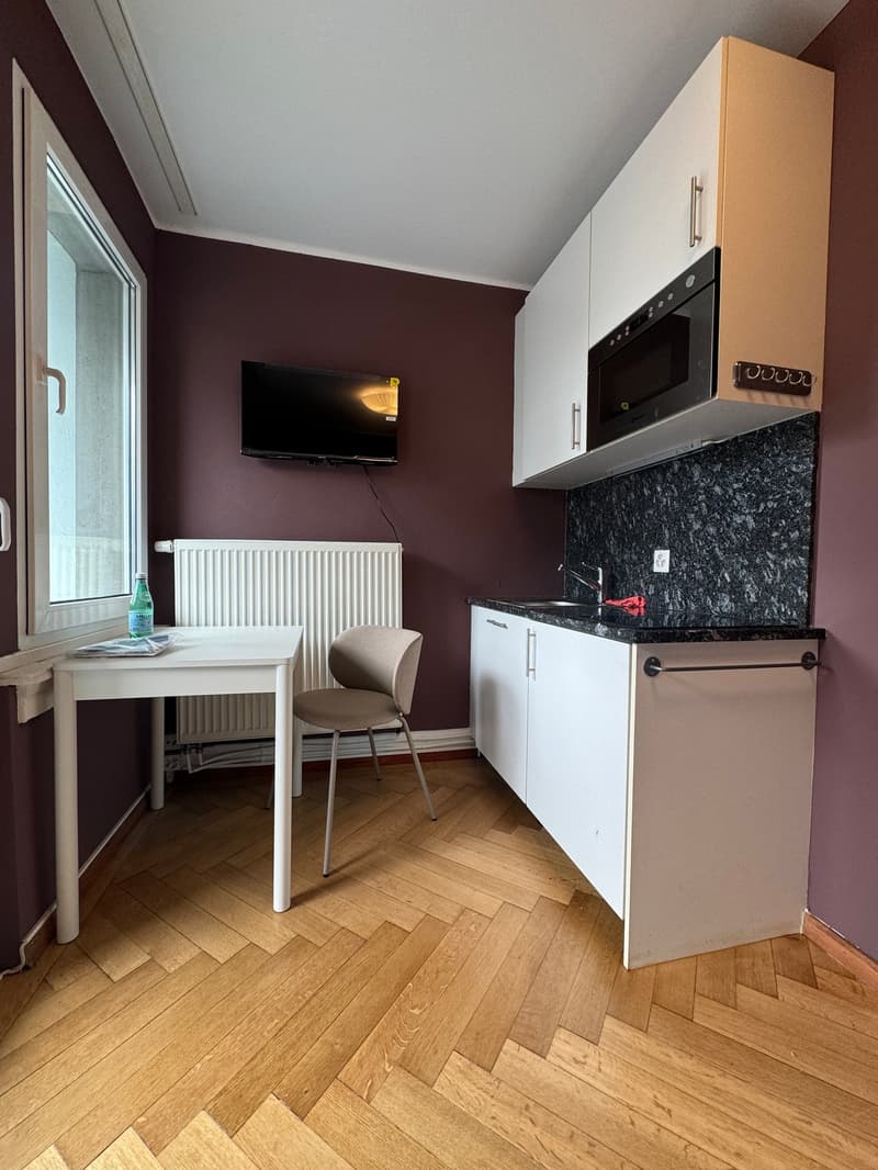 small kitchen with table, chair, microwave, sink, radiator, TV, window