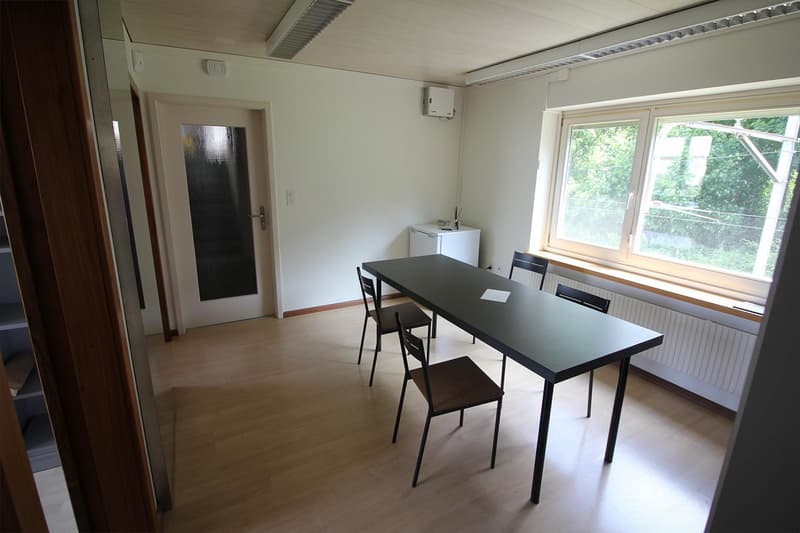 A square long table, 4 chairs, radiator, door, windows