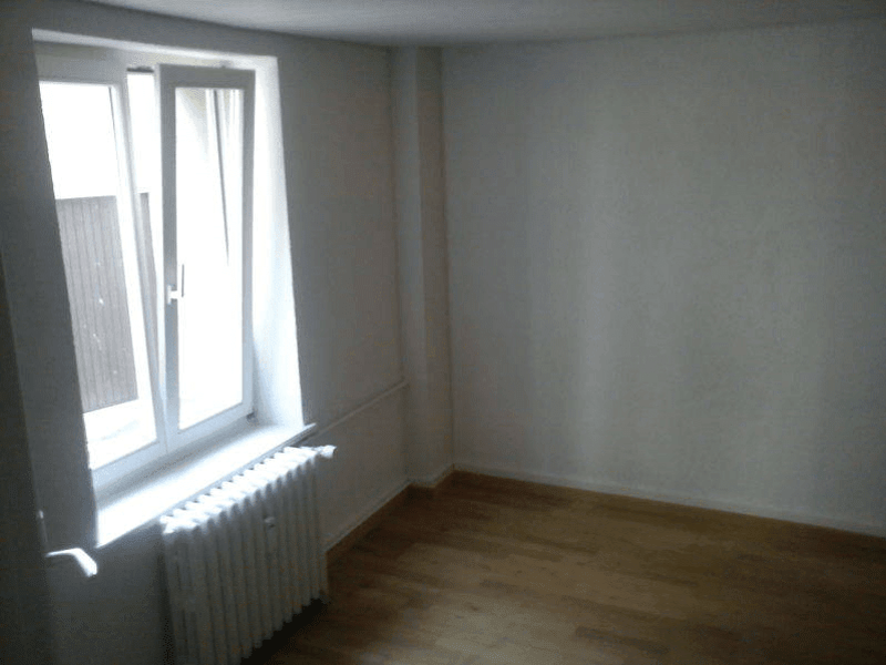 Empty room, white walls, wooden floor, window with radiator, small window above