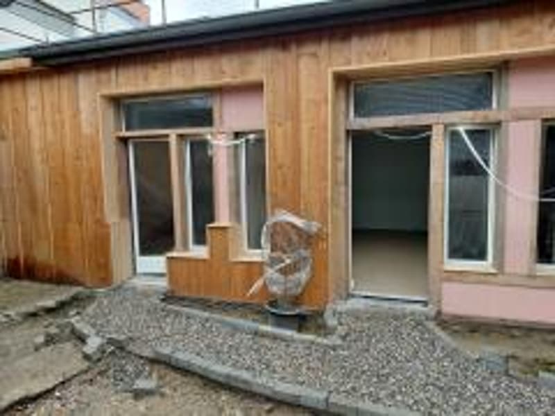 Modern house under construction, wooden exterior, two windows, gravel path to entrance