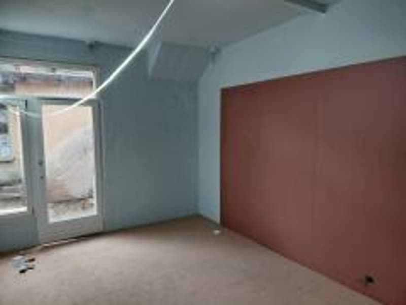 Empty room with white and red walls, glass doors, large window, beige floor.
