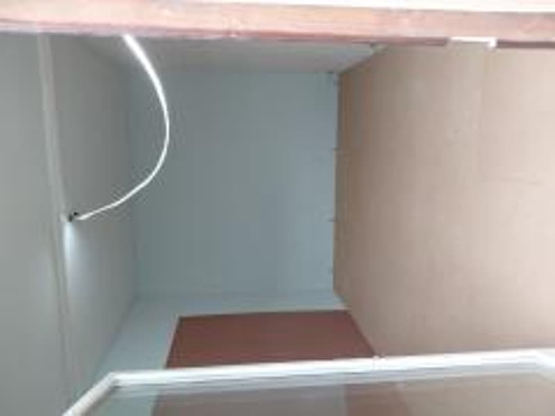 Empty room with painted walls and brown floor, white ceiling, small glass window.