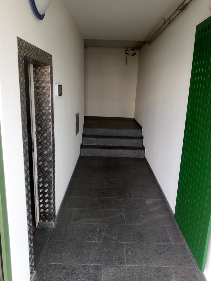 tiled floor, white walls, elevator, stairs, green door