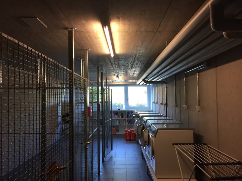 tiled floor, row of washing machines, drying racks, shelf with items