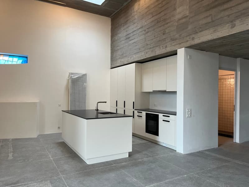 White kitchen with large countertop, black countertops, built-in oven, minimalist design, cement floor, modern fixtures, glass windows