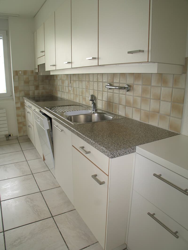 White cabinets, tile floor, granite countertop, stainless steel sink, white dishwasher, faucet