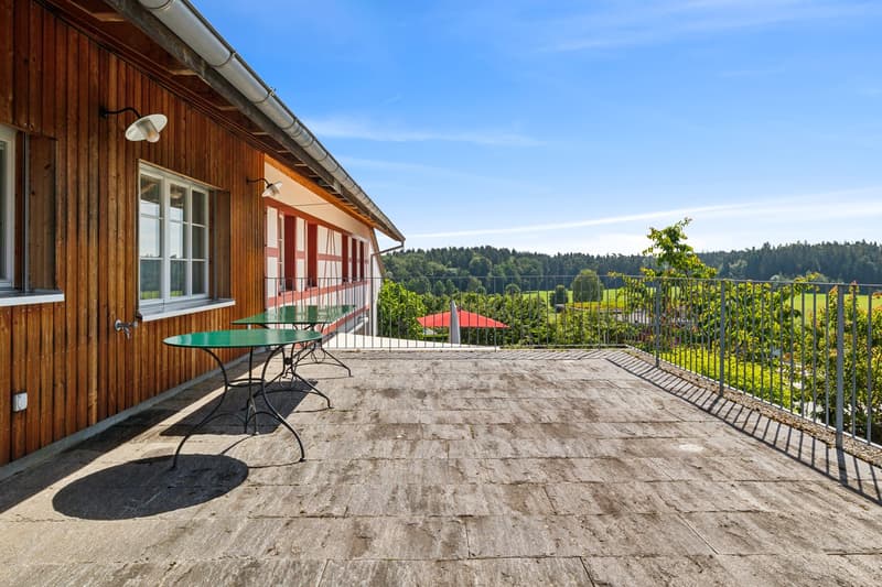 wooden terrace, metal railings, 2 green tables, wooden house, beautiful view