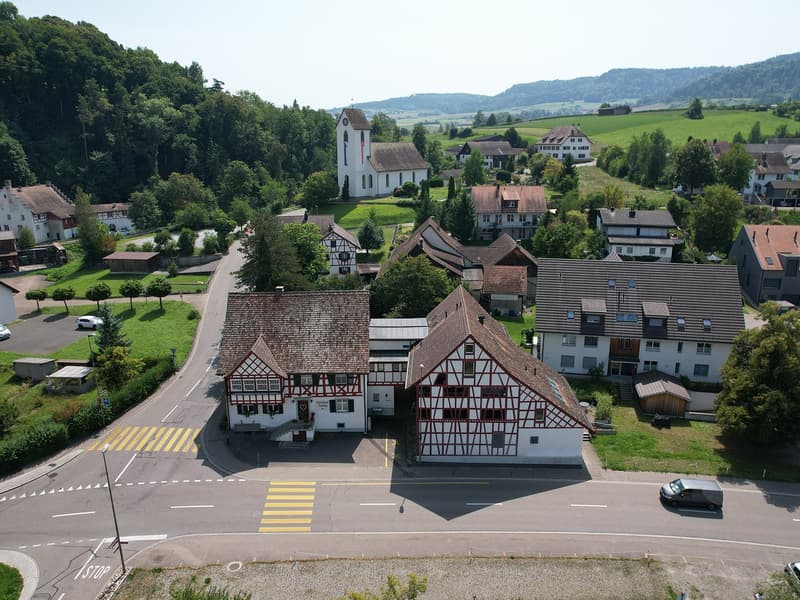 The village has several buildings, mostly two-story houses, with a central church and a wide open space for parking.