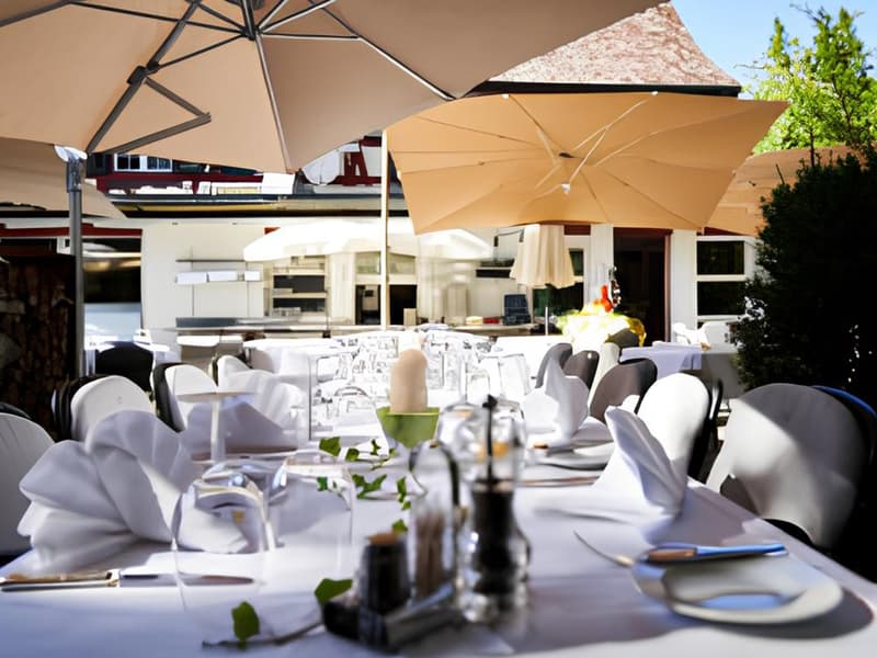 large dining area with multiple tables, under large umbrellas, on a balcony
