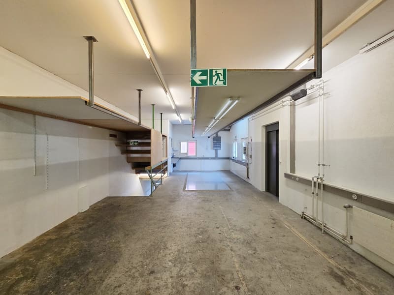 industrial looking parking garage with a staircase and an exit sign, empty