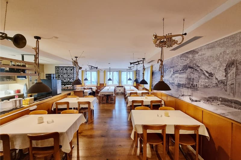 Modern restaurant, wooden tables, metal hanging lamps, large mural