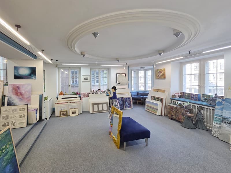 art gallery, carpeted floor, large windows, paintings on the wall, blue bench, sculptures, art pieces on display