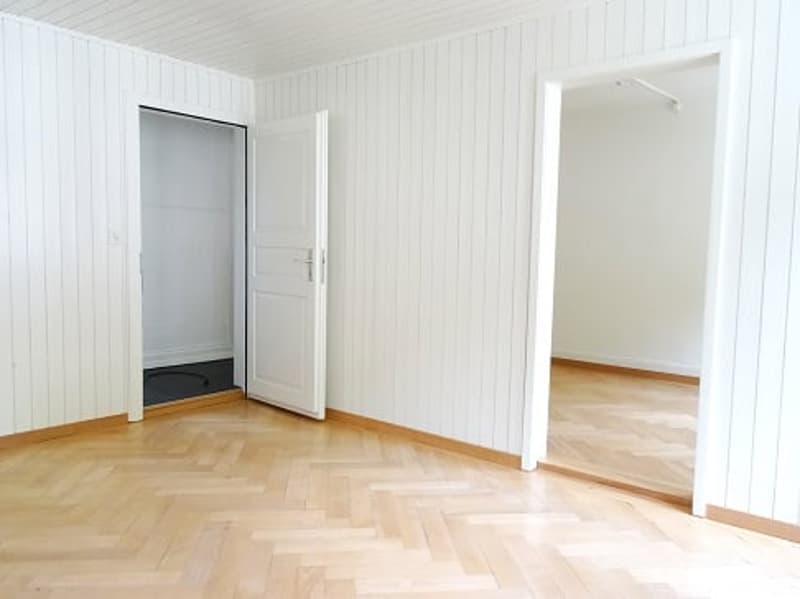 Empty room with wooden floor, white walls, two doors, one leading to a closet